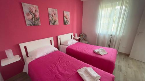 two beds in a room with pink walls at Fior di Luna in Stresa
