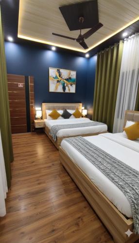 a bedroom with two beds and a blue wall at Amigo's Hotel and Restaurant in Nandaprayāg