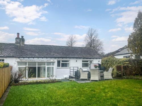 a white house with chairs in a yard at Garth Cottage in Keswick