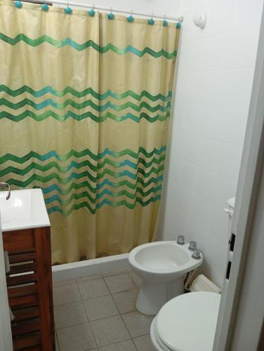 a bathroom with a shower curtain and a toilet at lo de Jor in Quequén