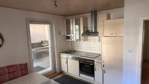 eine kleine Küche mit weißen Geräten und einem Fenster in der Unterkunft Elsbach-Perle in Oberelsbach