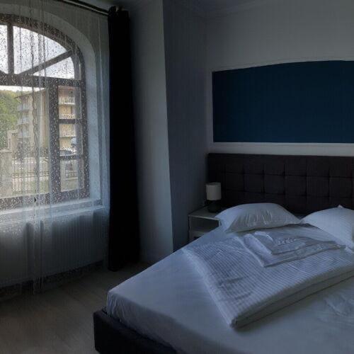 a bedroom with a bed with a large window at White Wood Chalet in Buşteni