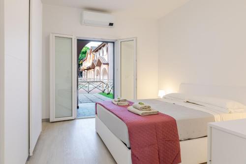 a white bedroom with a bed and a red table at Borgo Del Navigatore in Marina di Grosseto