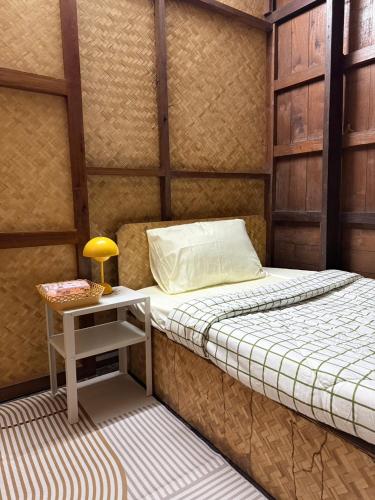a room with a bed and a table with a lamp at TEAK HOUSE In TOWN in Mae Hong Son