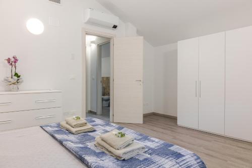 a white bedroom with two towels on a blue rug at Borgo Del Navigatore in Marina di Grosseto