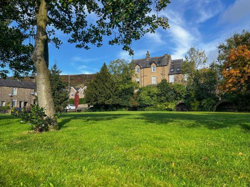 a large grassy field in front of a large house at Cracken Cottage - Uk48297 in Chinley