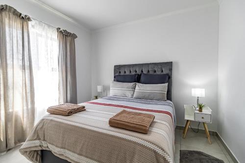 a white bedroom with a large bed with two pillows at Cozy Cove St Helena in West Point