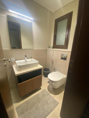 a bathroom with a sink and a toilet and a mirror at The Beach House in Muscat