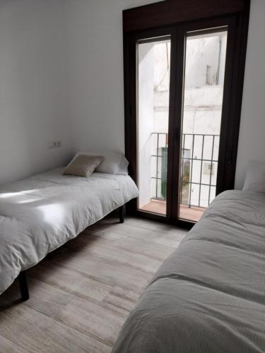 two beds in a room with a large window at Casa Rural "Baru" in Alpandeire