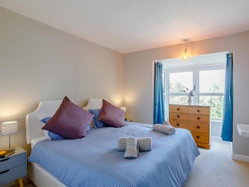 a bedroom with a bed with purple pillows and a window at 4 Bed in Mablethorpe oc-77958 in Sutton on Sea