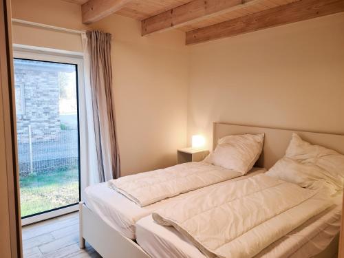 a bed in a room with a large window at Haus Lüchtje Jade in Sehestedt