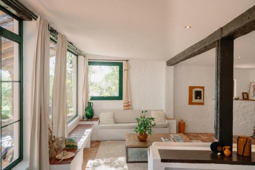a living room with a white couch and windows at Masia Can Pares in Sant Pere de Ribes