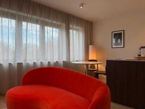 a red chair sitting in front of a window at L'Excelsior Suites in Brasschaat