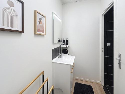 a white bathroom with a sink and a mirror at Le Antoine in Compiègne