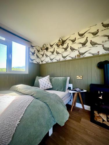 a bedroom with a bed and a bird mural on the wall at Cabin on the Moors in Llansannan