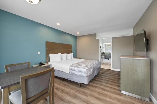 a hotel room with a bed and a desk and a television at Hotel Palmeras Chula Vista in Chula Vista