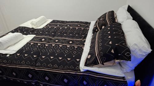 a bed with black and white sheets and pillows at The White House in Moston