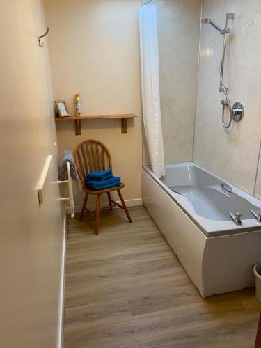 a bathroom with a tub and a wooden chair at Easter Corrie Cottages in Ballindalloch