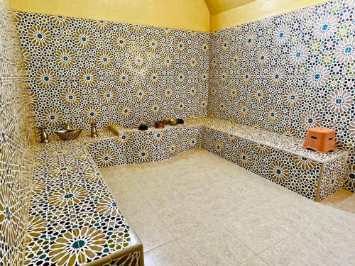 a bathroom with a tiled wall with a tub and a tub at Palais Aya in Oulad Akkou