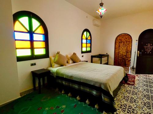 a bedroom with a bed and stained glass windows at Palais Aya in Oulad Akkou