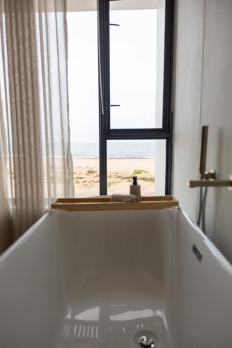 a bathroom with a tub and a window with the beach at Oceana View at Oceans 3 Selfcatering Holiday Home in Rand Rifles