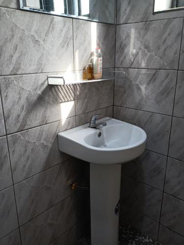 un bagno con un lavandino bianco e uno specchio di Chez Yenou a Cotonou