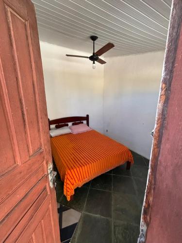 a bedroom with a bed with an orange comforter at Cantinho do tricolor in Saquarema