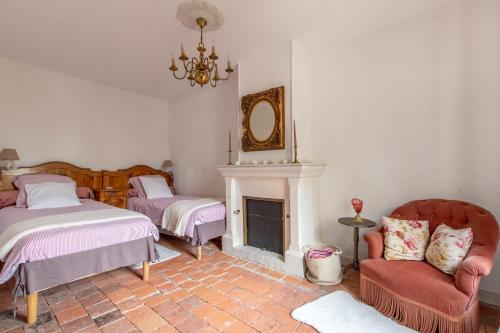 a living room with two beds and a fireplace at La Maison Haute in La Fosse-de-Tigné