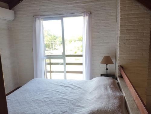 a bedroom with a white bed and a window at El Encuentro in Piriápolis