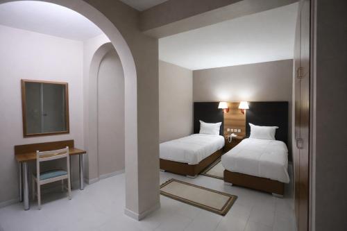 a bedroom with two beds and a table and a mirror at Hotel karim Tunis in Tunis