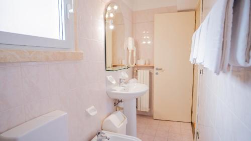 a bathroom with a sink and a toilet and a mirror at Hotel Al Pescador in Lazise