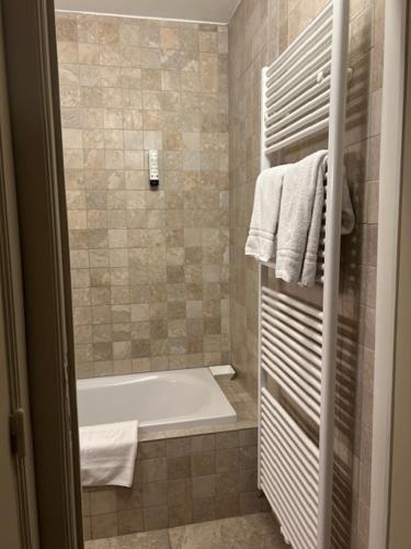 un bagno con vasca e doccia con asciugamani di Hotel Atlas a Zeebrugge