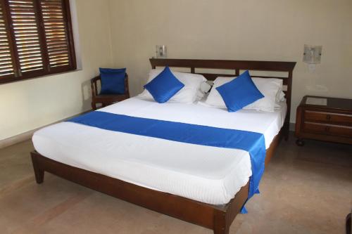 a bedroom with a large bed with blue pillows at Villa Inavni in Talawatugoda