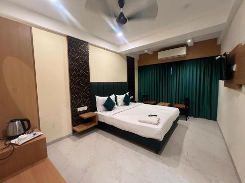 a bedroom with a large bed and a green curtain at Hotel Enigma in Indore