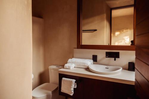 a bathroom with a sink and a toilet and a mirror at Luxury Apartment in Playa Blanca Zihuatanejo CAUMA in Zihuatanejo