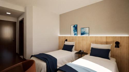 two beds in a hotel room with blue pillows at Matiz Barão Geraldo Express Hotel in Campinas