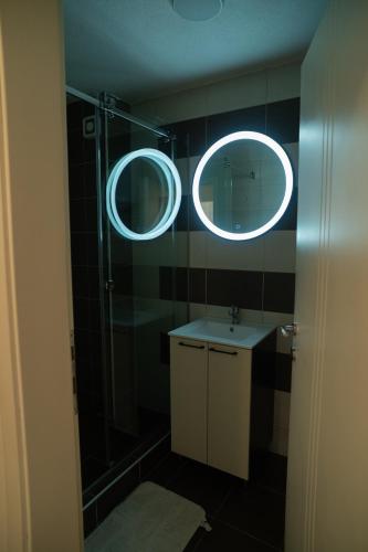 a bathroom with a shower and a sink and two mirrors at Nedodjija apartman in Leskovac