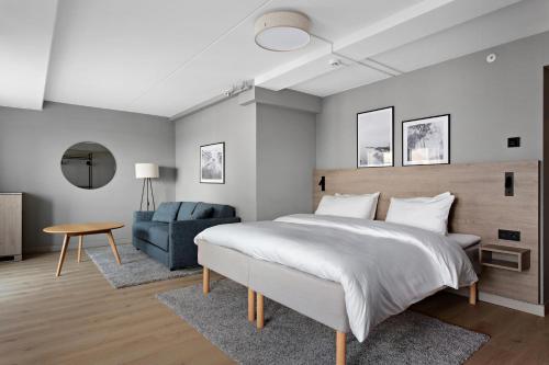 a bedroom with a large bed and a blue couch at Radisson Hotel Haugesund in Haugesund