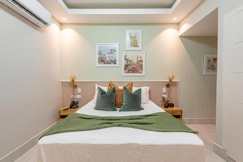 a bedroom with a large bed with green pillows at Hotel Stay Here Suites in Santo Domingo
