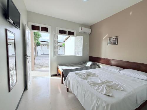 a bedroom with a bed and a tv and a window at Pousada Acalanto in Aracaju