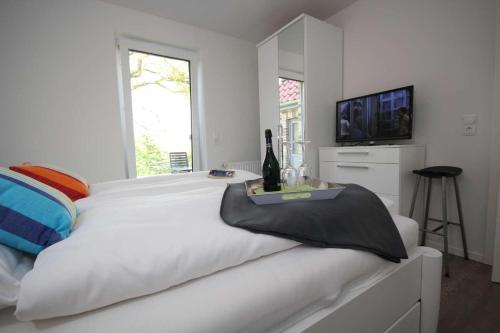 a white bedroom with a large white bed with a television at Feriendorf Südstrand Haus 11 in Pelzerhaken