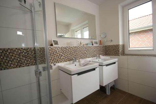 a bathroom with two sinks and a shower and a mirror at Feriendorf Südstrand Haus 11 in Pelzerhaken