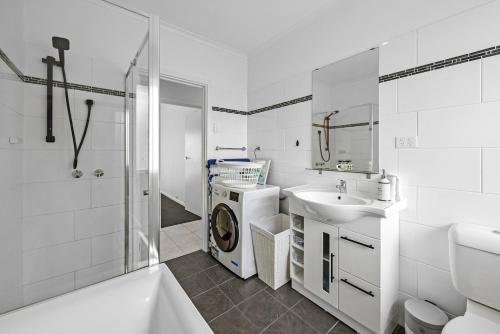 a white bathroom with a washing machine and a sink at Sunset Seas in West Beach in West Beach