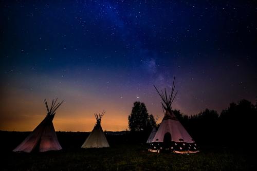 a group of three tents in a field at night at Fort Wapiti in Zalasowa