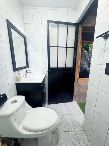 a white bathroom with a toilet and a sink at Garden Gathering Room in San Lucas Tolimán