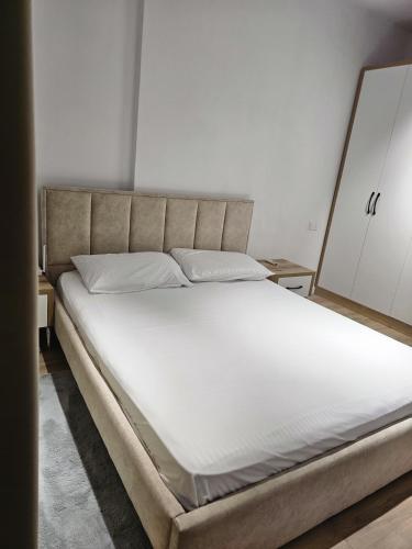 a bedroom with a large bed with white sheets at Tirana Apartment in Kashari