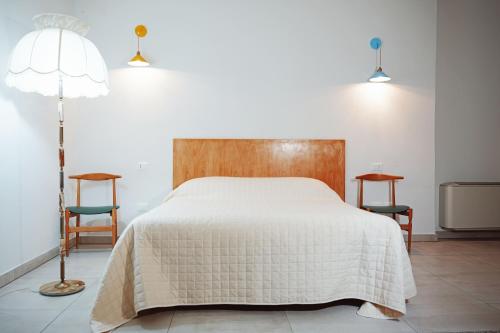 a bedroom with a bed and two chairs and a lamp at VAARAK in Bosa