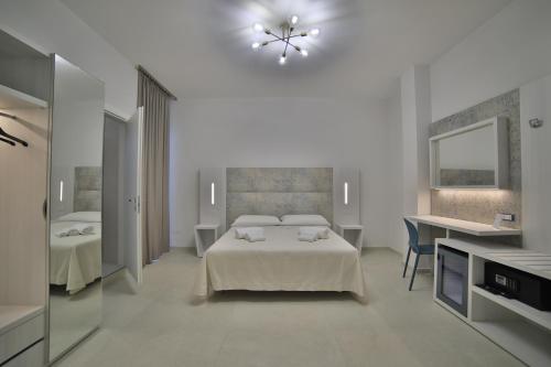 a white bedroom with a bed and a mirror at Hotel da ettore in Porto Cesareo
