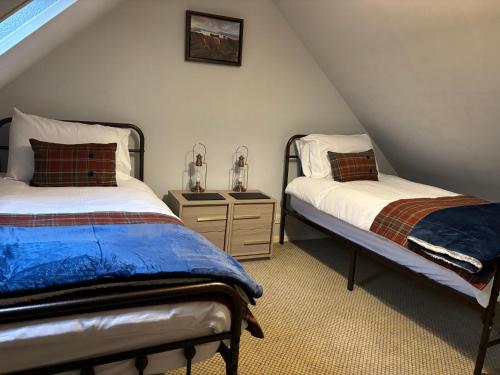 a attic bedroom with two beds and a night stand at Traditional 2 bed croft in Portskerra