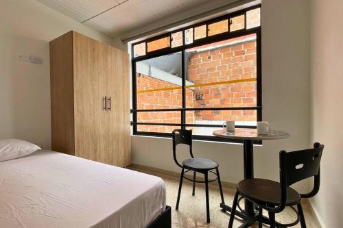 a bedroom with a bed and a table and a window at Edificio Casa Anita in Medellín